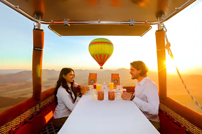 Romantic couple enjoying breakfast together in a hot air balloon over Marrakech on their honeymoon in Morocco