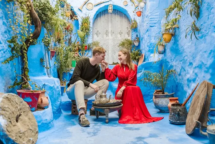 Romantic couple sharing mint tea in the blue city of Chefchaouen on their honeymoon Morocco tour