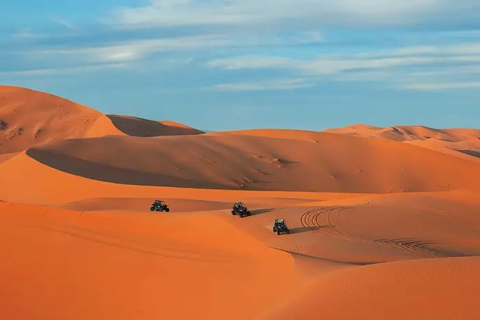 Desert buggies racing through the golden Sahara dunes of Erg Chebbi near Merzouga on a Morocco honeymoon all inclusive tour