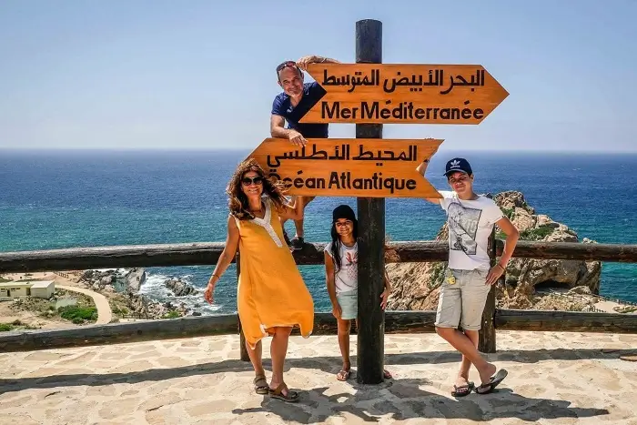A family posing at Cap Spartel in Tangier where the Atlantic Ocean meets the Mediterranean Sea on a Morocco 14 day itinerary