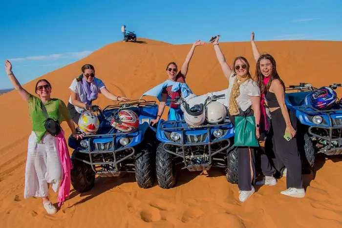 A group of tourists taking a picture after riding quad bikes on the golden Sahara Desert dunes of Erg Chebbi near Merzouga on a Morocco itinerary 14 days