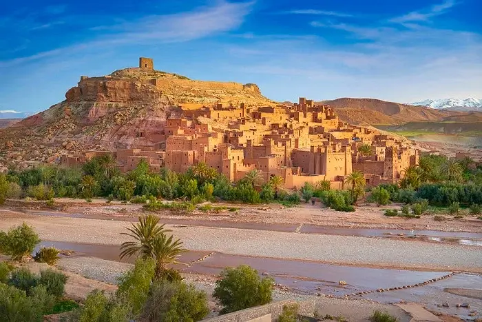 Panoramic view of the UNESCO World Heritage site of Ksar Aït Benhaddou with its red earth Kasbahs rising against the Atlas Mountains on a Morocco itinerary 2 weeks